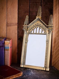 a mirror sitting on top of a wooden table next to a book case and some books