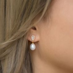 a woman wearing a pair of earrings with pearls on the bottom and an attached earring