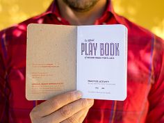 a man holding up a play book in his hand with the title written on it