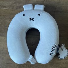 a white stuffed animal pillow sitting on top of a wooden floor