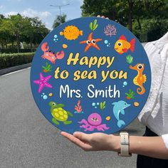 a woman holding up a sign that says happy to sea you mrs smith on it