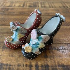 two ceramic shoes with flowers on them sitting on a wooden floor