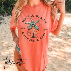 Trendy Malibu Beach surf shop t-shirt printed on comfort colors tee. Direct to garment printing.  *If you want this shirt oversized, please size up* Comfort Colors introduces its garment-dyed t-shirt;  made 100% with ring-spun cotton. The soft-washed, garment-dyed fabric brings extra coziness to your wardrobe while the relaxed fit makes it an excellent daily choice. The double-needle stitching throughout the tee makes it highly durable while the lack of side-seams helps the shirt retain its tubu Summer Surfing Vsco T-shirt, Trendy Cotton T-shirt For Surfing, Vsco Style Short Sleeve T-shirt For Beach Season, Beachy Crew Neck T-shirt For Surfing, Graphic Tee Soft-washed T-shirt For Surfing, Beachy Crew Neck Top With Screen Print, Vacation Crew Neck T-shirt In Vsco Style, Pink Graphic Print Top For Summer Adventures, Pink Graphic Print Tops For Summer Adventures