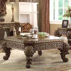 an ornately decorated coffee table in front of a fireplace with candles on the mantle