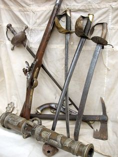 an assortment of old tools are displayed on a white cloth covered surface with a curtain in the background