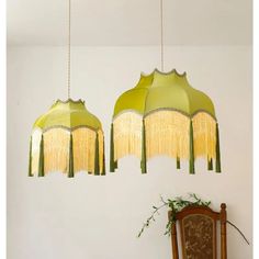 two green lamps hanging from the ceiling in a room with a wooden chair and table