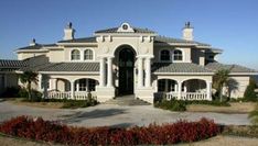 a large white house sitting on top of a lush green field next to the ocean