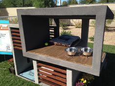 a dog house made out of concrete with two bowls on the top and one bowl in the middle