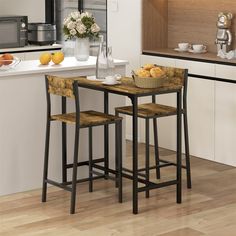 a kitchen table with two stools next to it and some fruit on the counter