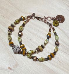 "Rustic and earthy double strand boho bracelet, great for everyday. This was created using a Czech glass bicone bead in cream and etched with a brown wash as a focal, Czech Picasso glass beads in sage, camel, cream, and a dark mustard.  I have also used antique copper accent beads throughout.  The extender chain is finished with a green Czech glass flower bead, and a copper dragonfly charm.    Bracelet best fits a wrist size between 6-3/4\" - 7-1/2\".  If a longer extender is needed, please leav Hippie Green Bracelet Jewelry, Handmade Adjustable Copper Beaded Bracelets, Bohemian Multi-strand Bracelets For Beach, Adjustable Rustic Green Bracelets, Adjustable Multi-strand Festival Bracelets, Adjustable Beaded Nature-inspired Bracelet, Adjustable Rustic Green Bracelet, Gold Multi-strand Bohemian Bracelets, Bohemian Multi-strand Gold Bracelets