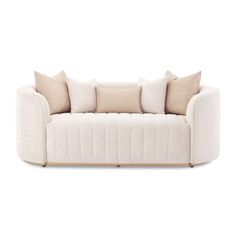 a white couch with pillows on it and two beige pillows hanging from the armrests