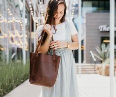 Tote bags are a recent trend in the handbag fashion world, so be fashionably up-to-date with this Personalized Full Grain Leather Tote Bag for you to look stylish and be stylish! Handmadewith love and care in Austin, Texas, our Abbie pocketed tote bag is dashingly chic to those of you who strive to be swank. Stand out from the crowd as our Classic Abbie Brown Purse in Leather is sophisticatedly crafted from premium full-grain leather and is water-resistant as well as made to withstand daily use Smooth Grain Crossbody Bag For Shopping, Everyday Smooth Grain Bags, Trendy Bags With Leather Handles As A Gift, Elegant Bags With Leather Handles For Gifts, Smooth Grain Satchel Shoulder Bag As A Gift, Smooth Grain Satchel Shoulder Bag Gift, Smooth Grain Leather Shoulder Satchel As Gift, Brown Leather Tote Bag, Brown Purse