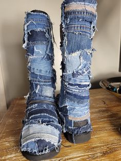 a pair of blue jean boots with torn up jeans on the bottom and sides, sitting on top of a wooden table