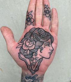 a woman's hand with tattoos on it and flowers in her hair is shown