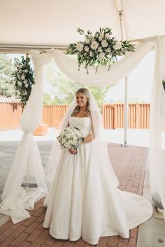 a woman in a wedding dress standing under a canopy