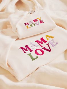 two personalized baby ones laying on top of a white sheet with the words, baby love and mama love