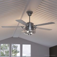 a ceiling fan in a large room with two windows and white siding on the walls