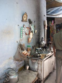 a man standing next to a stove in a room filled with pots and pans