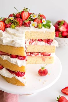 a triple layer cake with strawberries and cream frosting on a white platter