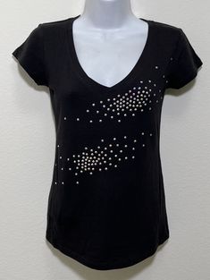 Fabric comprised of 95% cotton and 5% spandex.  Handmade rhinestone t-shirts made in the United States with quality rhinestones. Machine washable. T-shirt style is a fitted V-neck cap sleeve. AB stands for Aurora Borealis; this is the type of rhinestone used on our T-shirt creating a unique multi-dimensional shine. Size Range:         XXS = 2         XS = 4         S = 6         M = 8         L = 10         XL = 12 Fitted Black T-shirt With Rhinestones, Rhinestone Cotton Tops With Short Sleeves, Cotton Rhinestone Short Sleeve Top, Cotton Tops With Rhinestones And Short Sleeves, Cotton Short Sleeve Top With Rhinestones, Embellished Fitted Cotton T-shirt, Fitted Cotton Embellished T-shirt, Fitted Cotton Top With Rhinestones, Fitted Casual Tops With Rhinestones