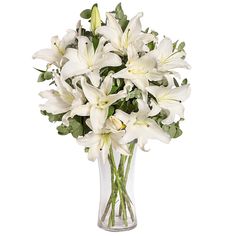 a vase filled with white lilies on top of a table next to a wall