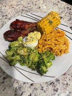 a white plate topped with meat, rice and broccoli next to corn on the cob