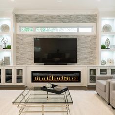 a living room with a fireplace, couches and a flat screen tv on the wall