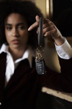 a woman holding up a car key to the camera