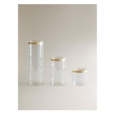 three clear glass jars with gold rims on white background, one is empty and the other has no lid