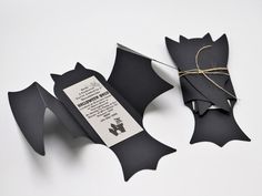 an origami bat cut out of black paper and tied with twine on white background