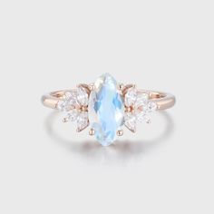 an oval blue topazte and diamond ring with three pear shaped diamonds on each side