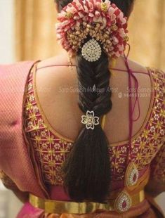 the back of a woman's head with braids and flowers in her hair