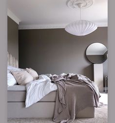 a large bed sitting in a bedroom next to a white ceiling lamp and round mirror