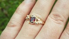 a woman's hand with a gold ring on it and a red stone in the middle