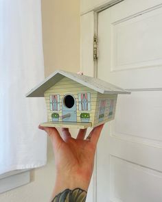 a person holding up a small bird house