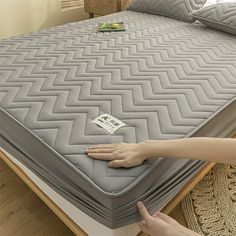 a woman is reaching for the mattress on her bed