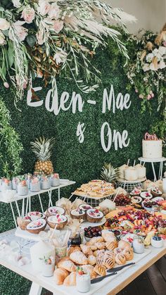 a table filled with lots of food next to a green wall