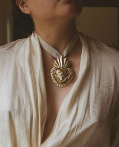 a woman wearing a white shirt with a gold heart pendant on it's neck