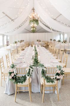 the tables are set up with white linens and greenery for an elegant wedding reception