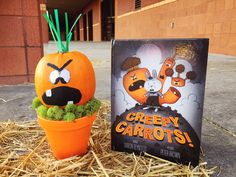 an orange pumpkin sitting next to a creepy carrots book on some hay and straw