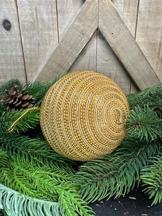 a yellow ball sitting on top of a green plant next to pine cones and needles