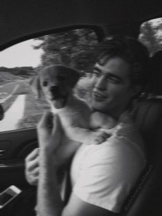 a man holding a dog in his arms while sitting in the back seat of a car