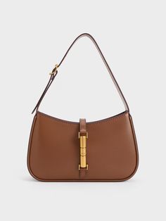 This product is made with at least 20% sustainable materials by weight. CHARLES & KEITH uses recycled, degradable, organic, and water-based materials in our eco-conscious collection. The Cesia minimalist design enhances its versatility, making it the perfect style companion for office hours, casual weekends, and everything in between. With its timeless combination of chocolate brown and metallic gold, it will add a touch of elegance to your everyday wardrobe, effortlessly elevating any look. The metallic gold accent serves not only as a decorative element but also as a functional magnetic closure, ensuring the safety and security of your personal belongings. Handbags Charles And Keith, How To Style Brown Bag, Everyday Brown Bag, Purse Dump, Charles And Keith Bags, Charles And Keith, Vetements Clothing, Accessorize Bags, Dream Bags