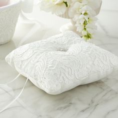 a white pillow sitting on top of a marble counter next to a vase with flowers