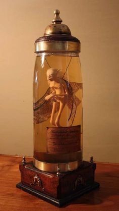 a glass jar with an angel in it sitting on top of a wooden table