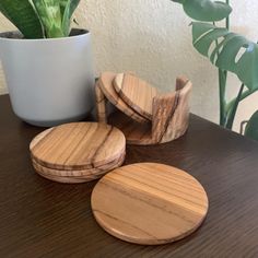 three wooden coasters sitting on top of a table next to a potted plant