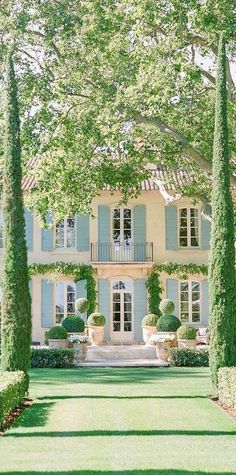 a large white house with blue shutters and trees