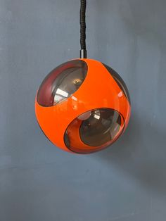 an orange and black light hanging from a hook on a gray wall in a room