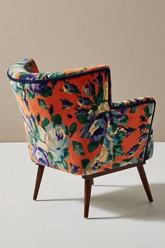 an orange and blue flowered chair on a white surface with a light brown wall in the background