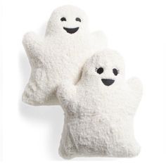 two white plush ghost pillows with black eyes and arms, one is holding the other's hand